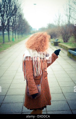 Belle jeune femme cheveux bouclés rouge au parc Banque D'Images