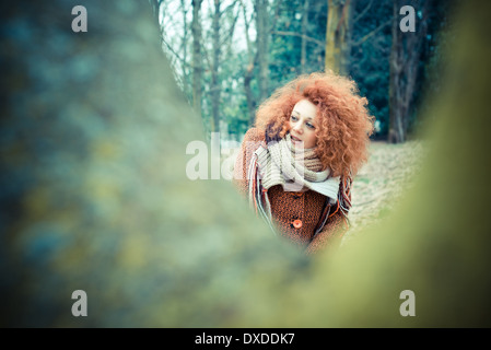 Belle jeune femme cheveux bouclés rouge au parc Banque D'Images