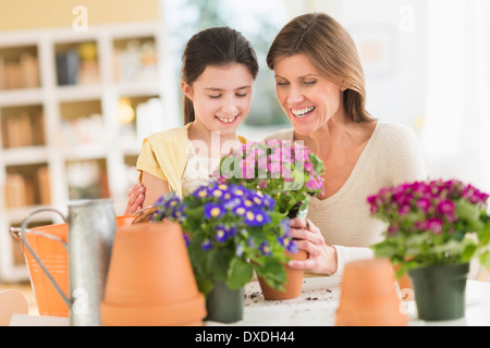 Girl (8-9) et la mère de fleurs en pot Banque D'Images