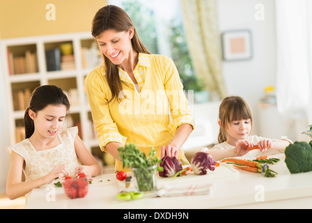 La mère et les filles (4-5,8-9) cooking in kitchen Banque D'Images