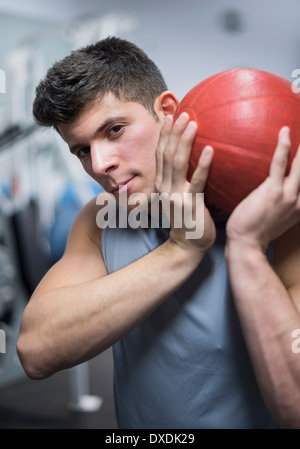 Jeune homme à gym holding medicine ball Banque D'Images