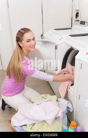 Femme en blanchisserie chargement lave-linge Banque D'Images