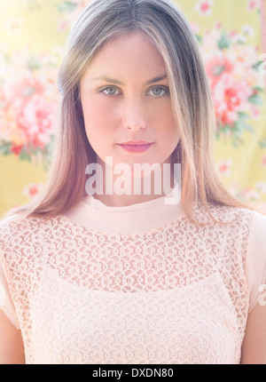 Portrait de jeune femme en face de papier peint floral Banque D'Images