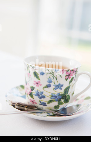 Tasse de thé dans la jolie tasse et soucoupe floral avec sachet de thé utilisé, studio shot Banque D'Images