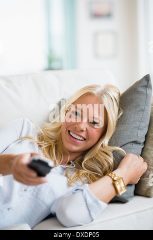 Jeune femme en regardant la télé sur canapé Banque D'Images