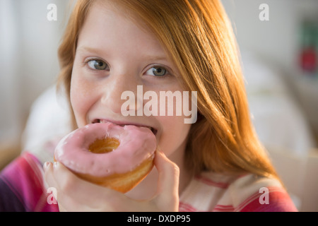 Portrait of Girl (12-13) eating donut Banque D'Images