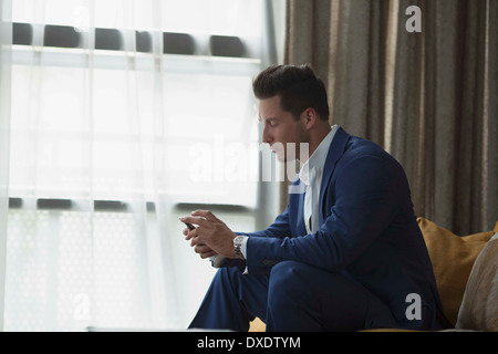 Jeune homme d'affaires assis à l'intérieur et de la messagerie texte, New York City, New York State, USA Banque D'Images