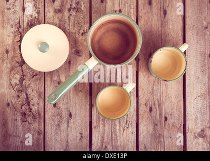 Vieilles tasses et casserole dans une table de cuisine rétro filtré de réglage Banque D'Images