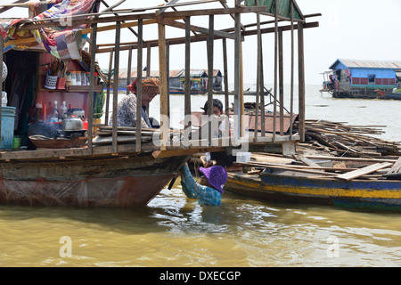 Homme dans l'eau réparant sa péniche sur le lac Tonle SAP dans le village flottant, Cambodge, Asie du Sud-est Banque D'Images