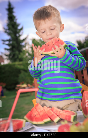 Petit garçon mangeant une pastèque dans le jardin Banque D'Images