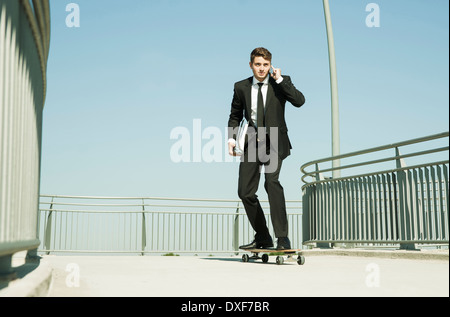 Businessman using Cell Phone while Skateboarding, Mannheim, Baden-Wurttemberg, Germany Banque D'Images