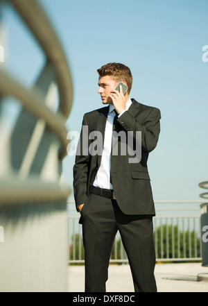 Portrait of businessman standing by railing et using cell phone, Allemagne Banque D'Images