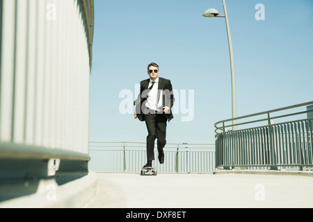 Businessman skateboarding sur walkway holding binder, Allemagne Banque D'Images