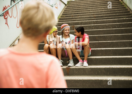 Garçon de regarder les filles assis sur des escaliers à l'extérieur, Allemagne Banque D'Images