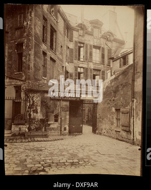 Photographie historique de la Cour de Rouen, située dans le passage du commerce dans le 6ème arrondissement de Paris. L'image capture l'architecture historique et le dynamisme du commerce parisien dans le passé. Banque D'Images