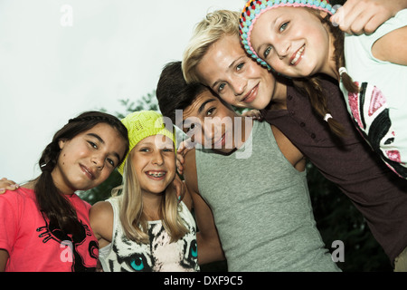 Groupe d'enfants se tenant ensemble avec les bras autour d'eath images and smiling at camera, Allemagne Banque D'Images