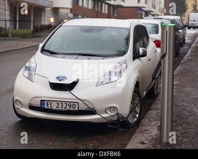 Voiture électrique Nissan en cours de charge, un parking public à Oslo en Norvège où il y a eu une augmentation rapide de leur nombre Banque D'Images