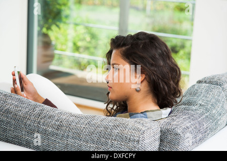 Close-up of teenage girl sitting on sofa looking at smart phone, Allemagne Banque D'Images