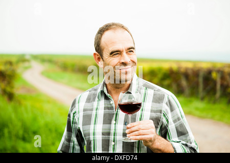 Portrait d'un viticulteur standing in vineyard, holding glass of wine, Rhénanie-Palatinat, Allemagne Banque D'Images