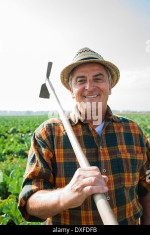 Portrait d'agriculteur avec pioche, debout et de travail dans le champ, Allemagne Banque D'Images