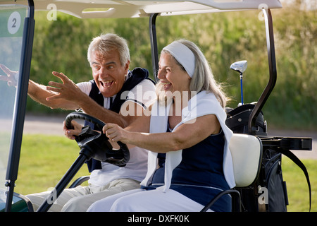 Mature couple riding in golf cart Banque D'Images