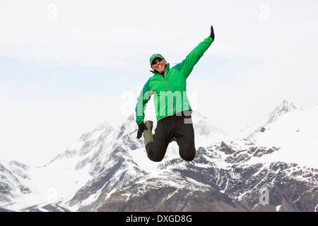 Un homme sauter de joie en face de montagnes au-dessus de Fortuna Bay sur la Géorgie du Sud dans l'océan Austral. Banque D'Images