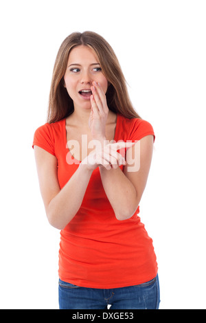 Young woman whispering et montrant quelque chose avec son doigt, isolated on white Banque D'Images