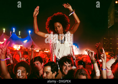 Cheering woman sur manÍs épaules à music festival Banque D'Images