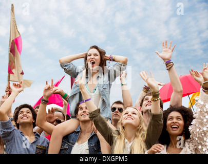 Cheering woman sur manÍs épaules à music festival Banque D'Images