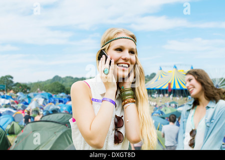 Woman talking on cell phone outside tents at music festival Banque D'Images