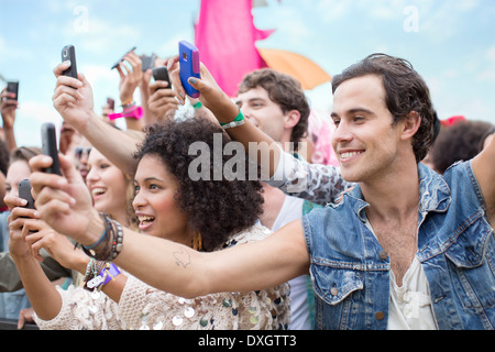 Téléphones portables avec appareil photo avec des fans cheering at music festival Banque D'Images