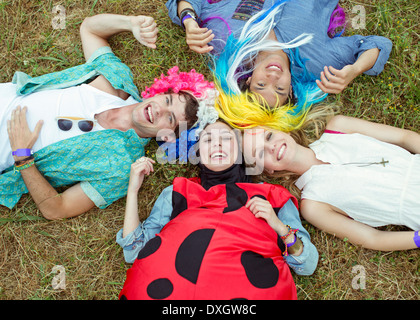 Portrait d'amis en costumes laying in grass at music festival Banque D'Images