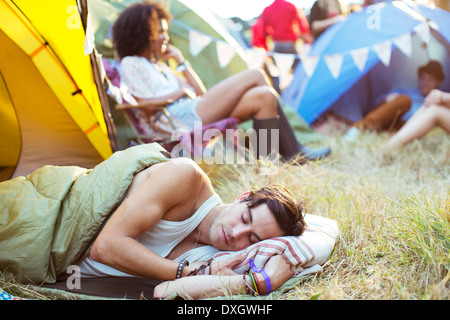 L'homme de dormir dans un sac de couchage à l'extérieur de la tente à music festival Banque D'Images