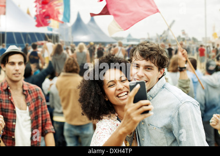 Couple taking self-portrait with camera phone at music festival Banque D'Images