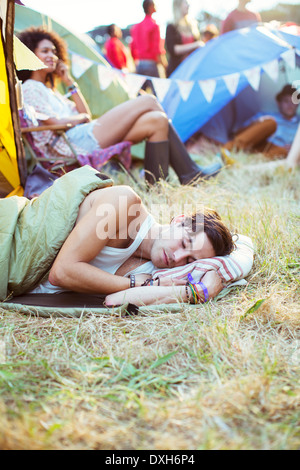 L'homme en sac de couchage tentes dormir dehors au festival de musique Banque D'Images