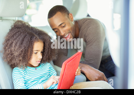 Père et fille using digital tablet in back seat of car Banque D'Images