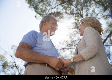 Happy senior couple holding hands under tree Banque D'Images