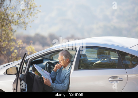 Senior man in car looking at map Banque D'Images