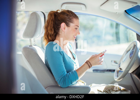 Femme textos avec téléphone cellulaire à l'intérieur de voiture Banque D'Images