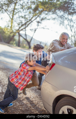 Multi-generation men poussant en bordure de voiture Banque D'Images