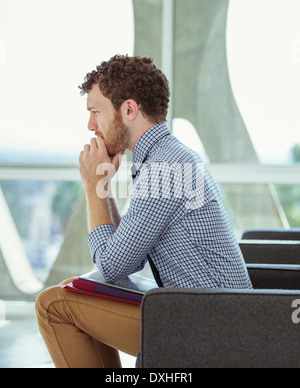 Pensive businessman sitting in office lobby Banque D'Images