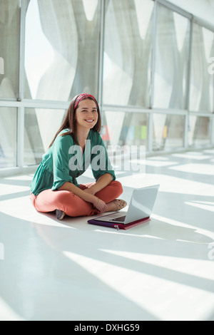 Portrait of smiling casual businesswoman using laptop in office ensoleillée Banque D'Images