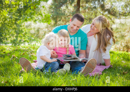 Jeune famille aime lire un livre ensemble dans le parc. Banque D'Images