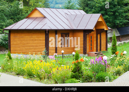 Petit village maison en bois avec lit de fleur Banque D'Images