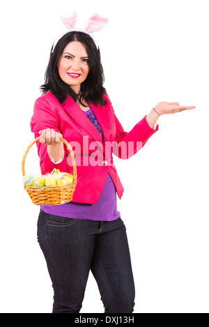 Femme avec des oreilles de lapin holding Easter basket avec des œufs et faire une présentation isolé sur fond blanc Banque D'Images