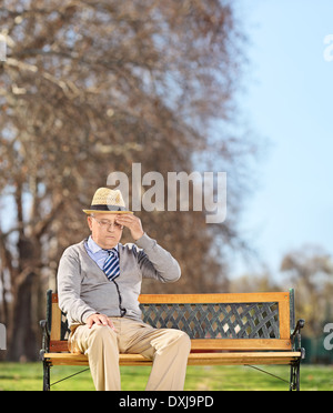 Senior man sitting in park et avoir un mal de tête Banque D'Images