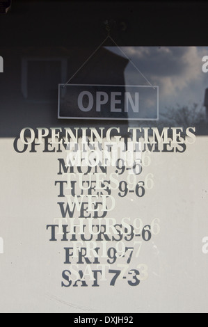 Temps d'ouverture d'une boutique peint sur un panneau de porte en verre, Chipping Ongar, Essex, Angleterre Banque D'Images