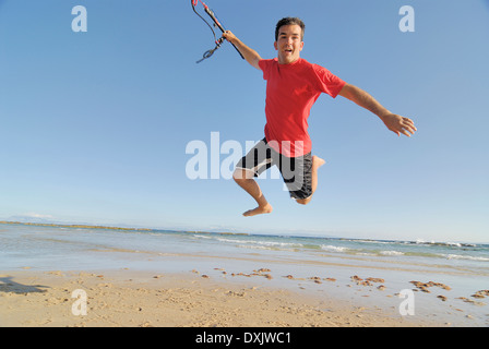 Homme kite surfer jumping on beach Banque D'Images