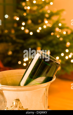 Bouteille de champagne vide dans le refroidisseur avec arbre de Noël en arrière-plan Banque D'Images