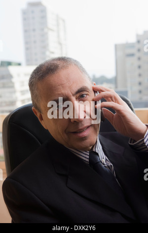 Portrait of Hispanic businessman talking on cell phone in office Banque D'Images